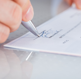 Close up of hand with pen signing a check